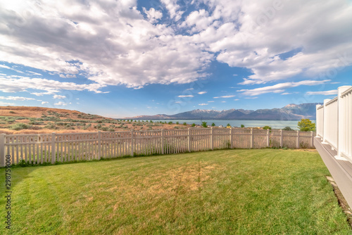 Bakyard with white wooden fence overlooking a scenic view of lake and mountain
