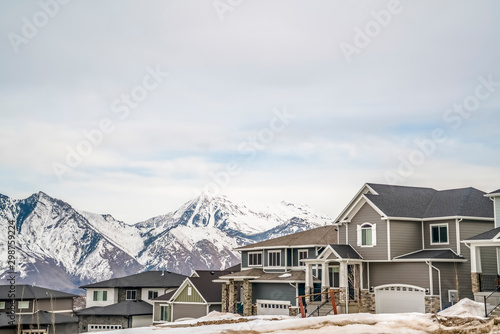 Winter neighborhood with homes viewed against snowy mountain and cloudy sky