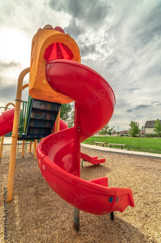 Close up on the colorful spiral slide at a park with cloudy sky background
