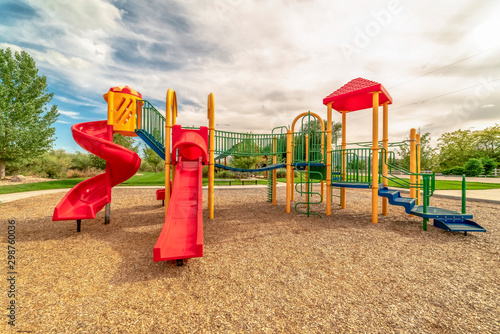Focus on empty childrens playground at a park with red slides and climbing bars photo
