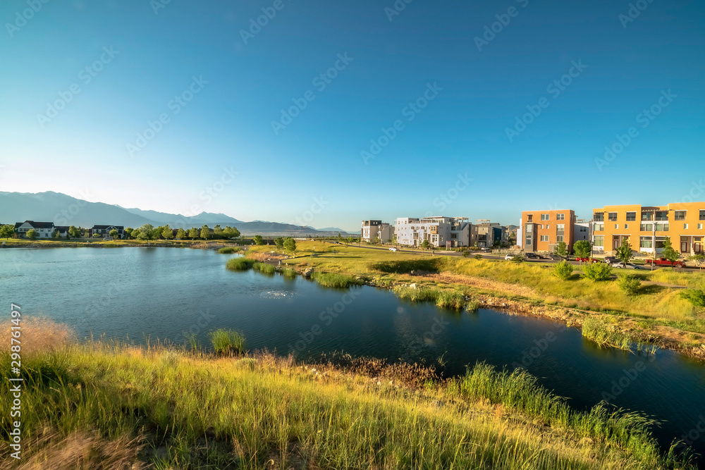 Beautiful lake amid grassy terrain with homes and buildings in the distance