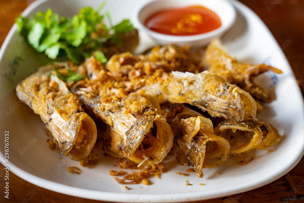 Closed up deep fried Thai style river fish (Sheatfish Fried) “Par Nae Non”, Traditional Thai Food with fried chopped garlic. Serverd with source. Delicious and yummy.