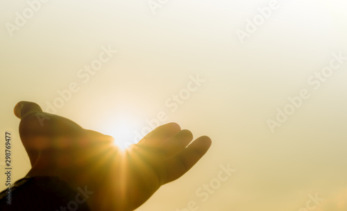 praying hands of a man for blessings his god through the sunset on sky background