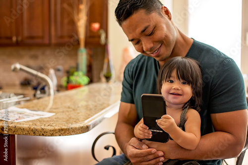 Father with his baby girl looking at cell phone