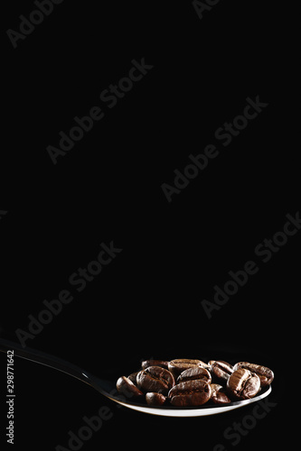 beverage background of roasted coffee beans in spoon isolated on dark background