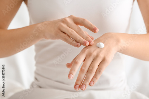 Young woman applying cream onto her hands, closeup