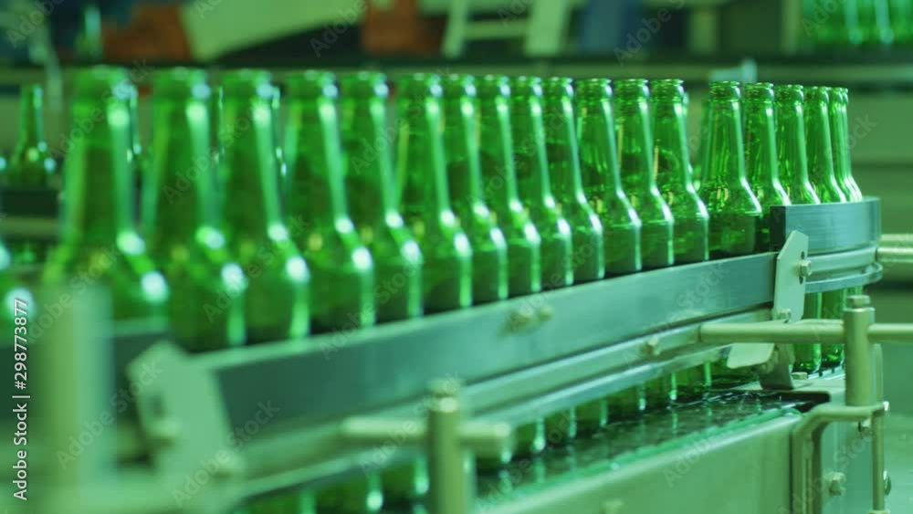 Green beer bottles is moving on the conveyor. Stages of production Green beer bottles is moving on the conveyor. Stages of production