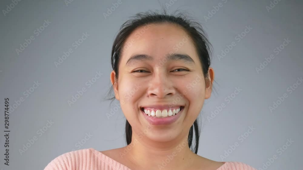 Young Asian woman with smiled expression on grey background. Young Asian woman with smiled expression on grey background.
