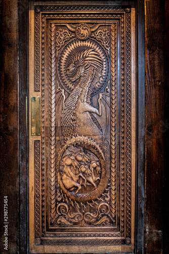 Photography BALLINTOY HARBOUR, NORTHERN IRELAND, DECEMBER 20, 2018: Magnificent carved door with dragons and Dothraki horses, made with wood from the Dark Hedges