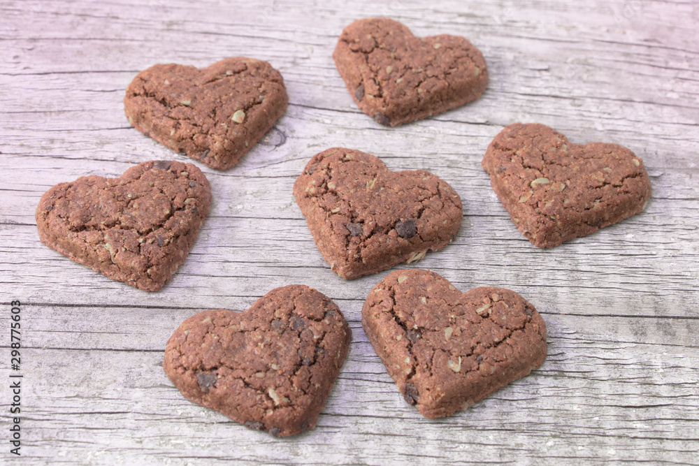 Obraz premium Heart shaped chocolate chip cookies on pastel wood.Concept of giving love , valentines day