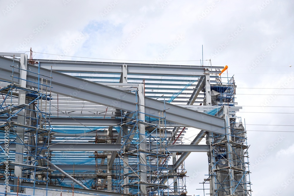 The structure of building with blue sky and clound as a background, Steel construction in large construction site, Space for text in template The structure of building with blue sky and clound as a background, Steel construction in large construction site, Space for text in template