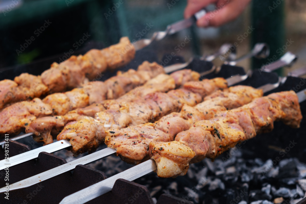 Shish kebab roasting on the grill. BBQ party. Close-up. Marinated shashlik preparing on a barbecue grill over charcoal.