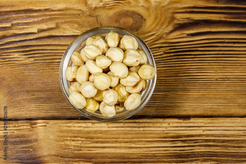Peeled hazelnuts in glass bowl on wooden table. Top view Peeled hazelnuts in glass bowl on wooden table. Top view