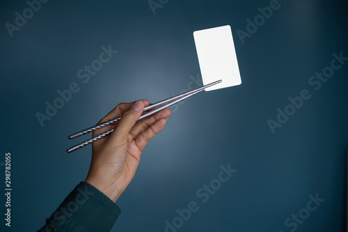 Hold holding chopsticks on a blank piece of paper. Close up White business card.