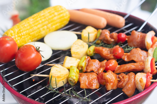 Colorful BBQ Grilling with pork ,sausage,tomato,onion,pineapple,chilli and corn on portable barbecue outdoor.