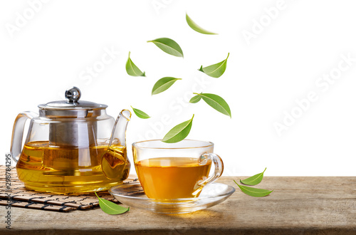 Jug and hot tea glass cup with flying whirl green tea leaves in the air, Healthy products by organic natural ingredients concept, Empty space in studio shot isolated on white background