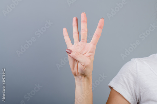 female hand in fist showing four fingers isolated over grey photo