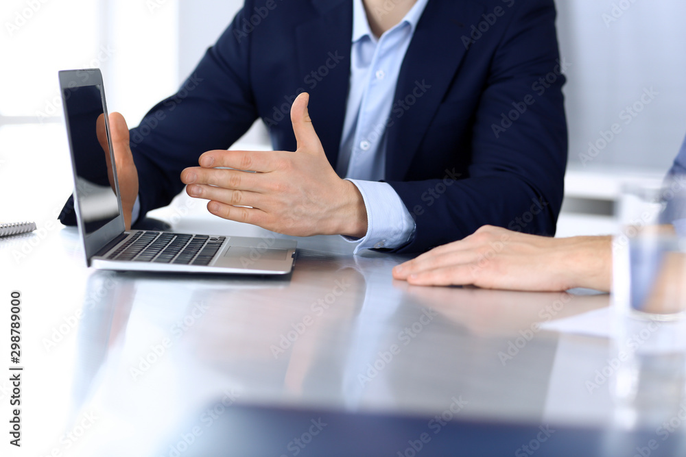 Business people using laptop computer while working together at the desk in modern office. Unknown businessman or male entrepreneur with colleague at workplace. Teamwork and partnership concept Business people using laptop computer while working together at the desk in modern office. Unknown businessman or male entrepreneur with colleague at workplace. Teamwork and partnership concept