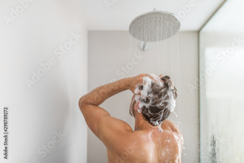 Fotografiet Man taking a shower washing hair under water falling from rain showerhead in luxury walk-in bath