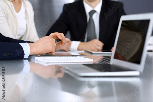 Business people discussing contract working together at meeting at the glass desk in modern office. Unknown businessman and woman with colleagues or lawyers at negotiation. Teamwork and partnership