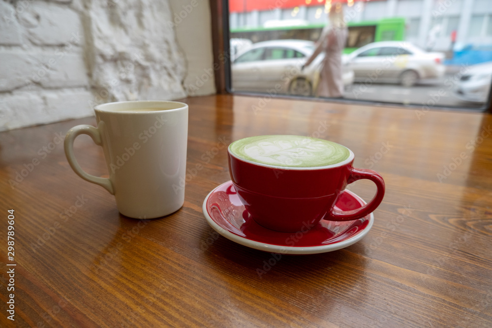Obraz premium couple of cups with coffee and matcha tea on a vintage wooden table in a coffee shop