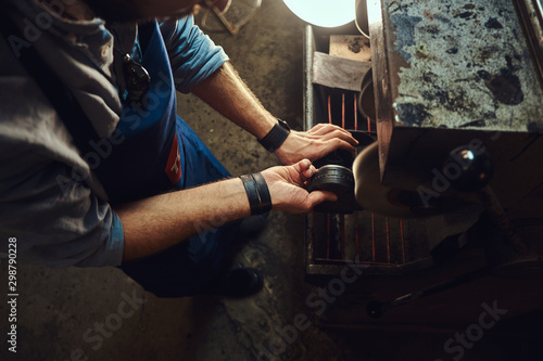 Hands of shoe master, which is working on shoe sole, using special machine tool.