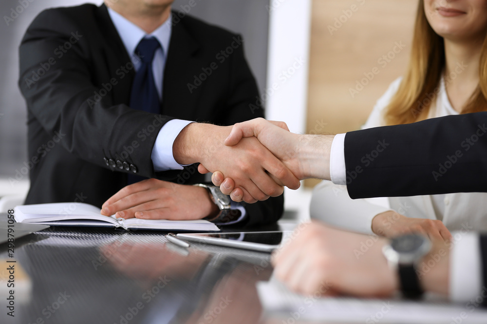 Businessman shaking hands with his colleague or partner above the glass desk in modern office, close-up. Unknown business people at meeting. Teamwork, partnership and handshake concept Businessman shaking hands with his colleague or partner above the glass desk in modern office, close-up. Unknown business people at meeting. Teamwork, partnership and handshake concept