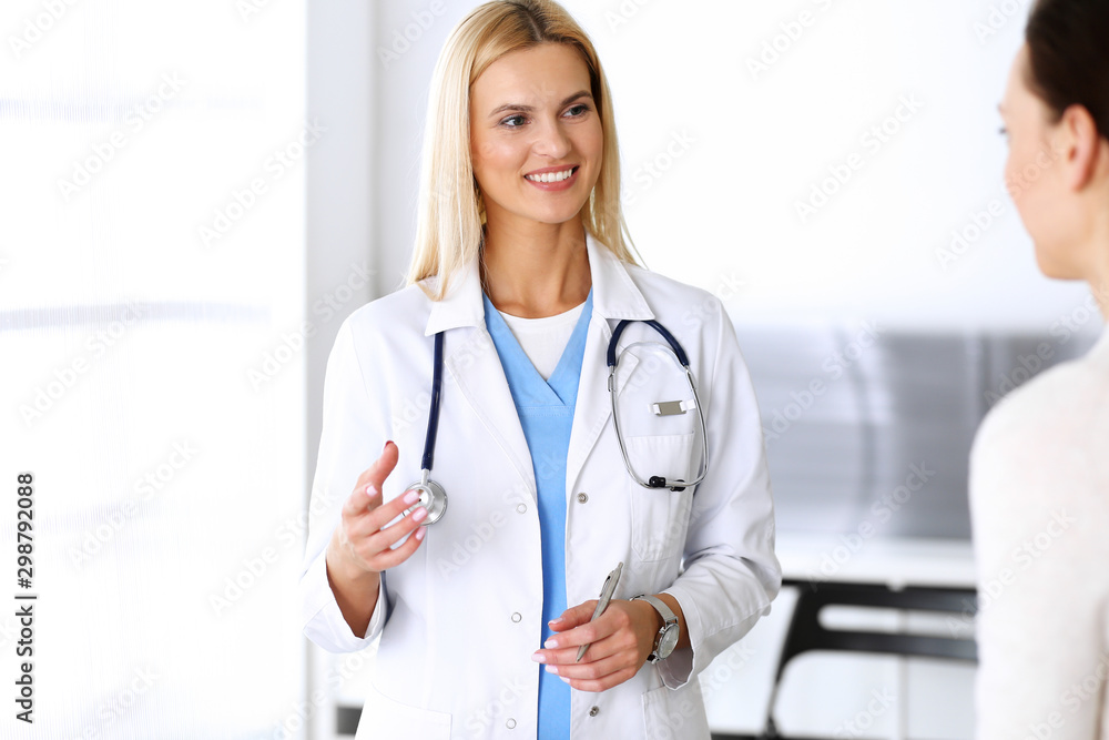 Doctor woman at work in hospital excited and happy of consulting female patient. Blonde physician controls medication history records and exam results while using clipboard. Medicine and healthcare Doctor woman at work in hospital excited and happy of consulting female patient. Blonde physician controls medication history records and exam results while using clipboard. Medicine and healthcare