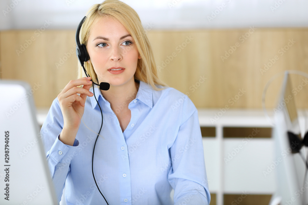 Call center. Blonde business woman sitting in headset at customer service office. Concept of telesales business or home office occupation Call center. Blonde business woman sitting in headset at customer service office. Concept of telesales business or home office occupation