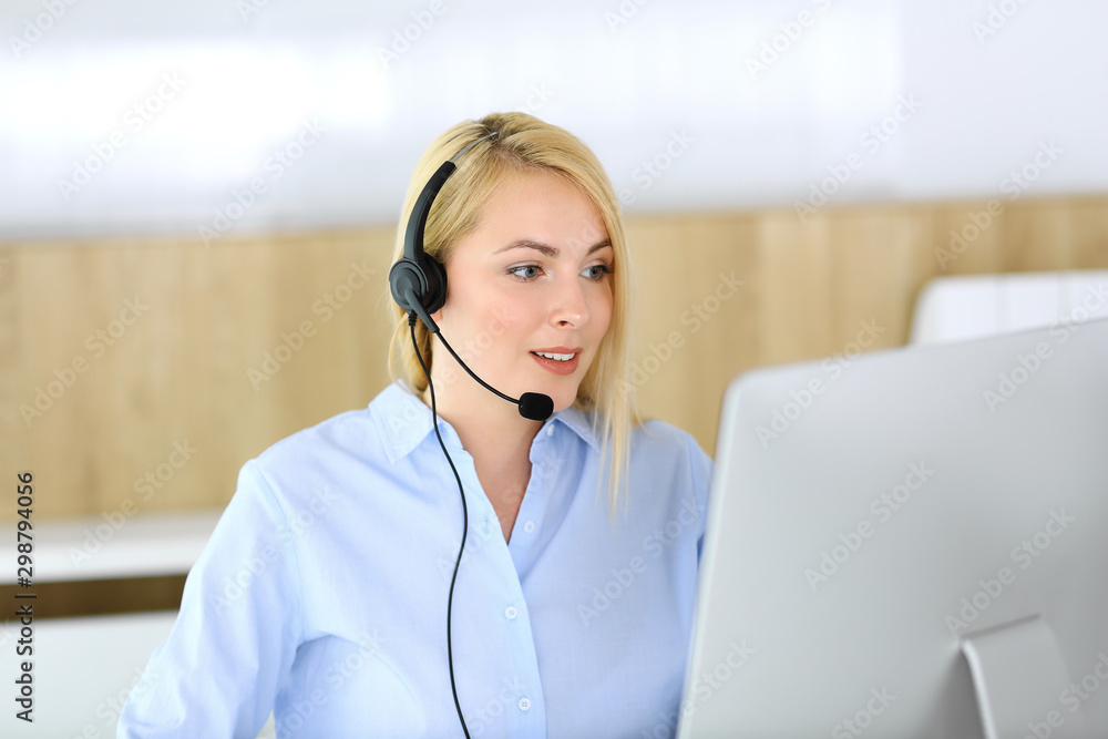 Call center. Blonde business woman sitting in headset at customer service office. Concept of telesales business or home office occupation Call center. Blonde business woman sitting in headset at customer service office. Concept of telesales business or home office occupation