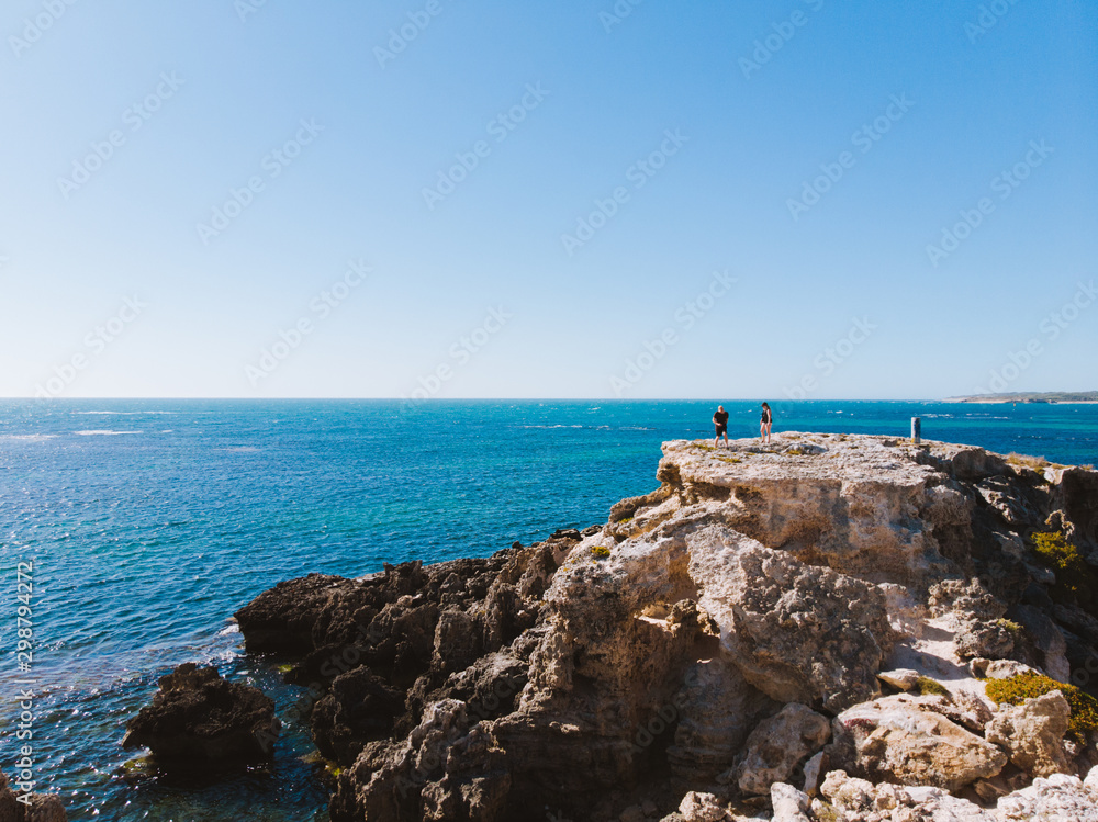 People on a cliff edge near the beautiful blue peaceful ocean of Rottnest Island, Perth, Western Australia. 