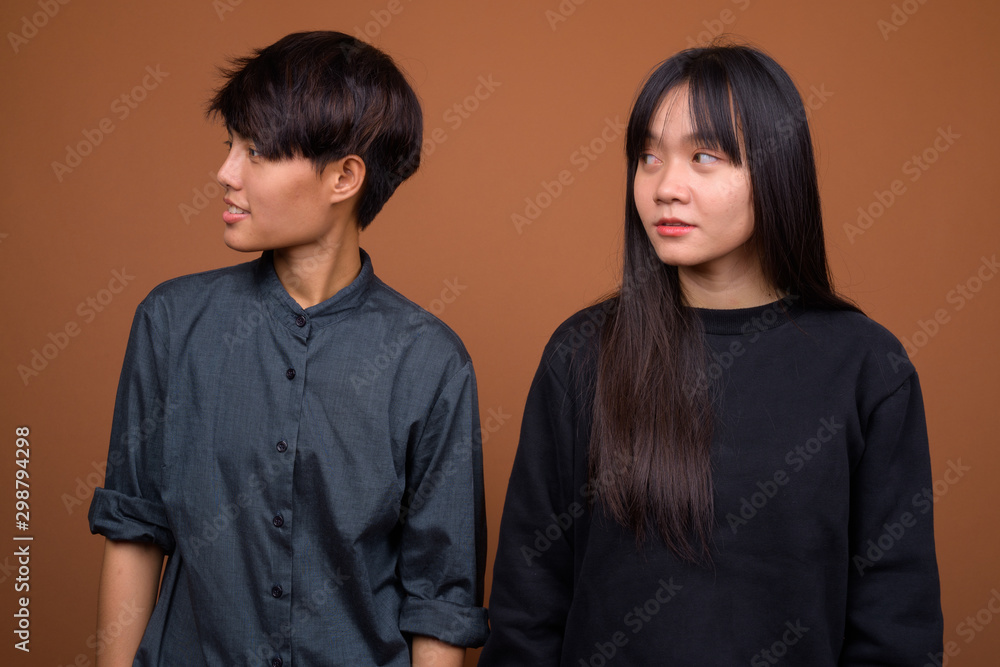 Young Asian lesbian couple together and in love against brown ba Young Asian lesbian couple together and in love against brown ba