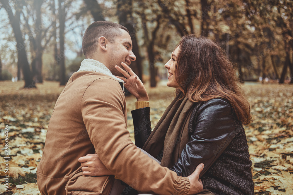 Attractive couple have fun while sitting at autumn park full of golden leaves. Attractive couple have fun while sitting at autumn park full of golden leaves.