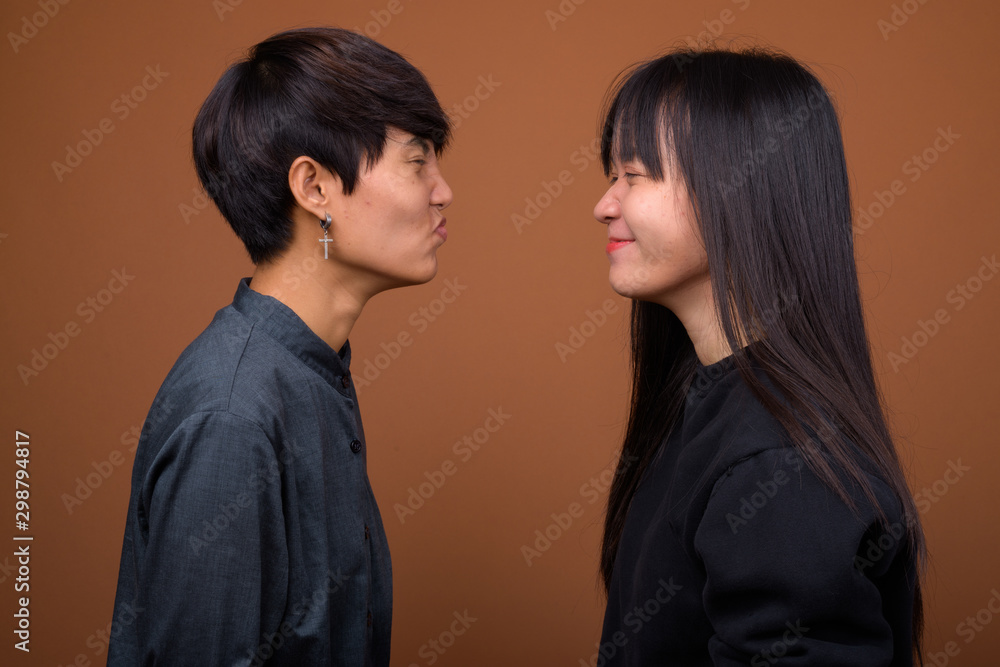 Young Asian lesbian couple together and in love against brown ba Young Asian lesbian couple together and in love against brown ba