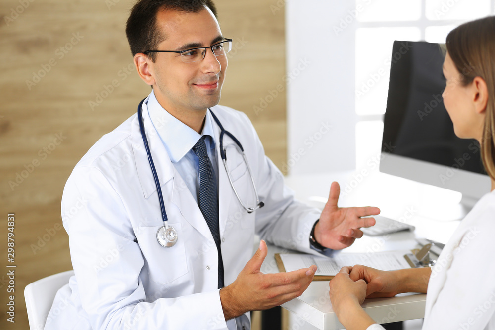 Doctor and patient discussing the results of a physical examination while sitting at a desk in a clinic. Medicine and Healthcare Concepts Doctor and patient discussing the results of a physical examination while sitting at a desk in a clinic. Medicine and Healthcare Concepts