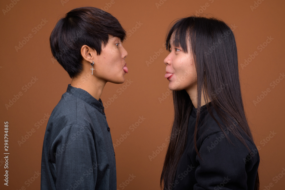 Young Asian lesbian couple together and in love against brown ba Young Asian lesbian couple together and in love against brown ba
