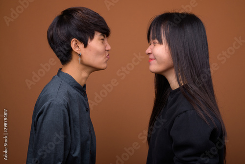 Young Asian lesbian couple together and in love against brown ba