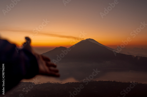 Batur volcano sunrise in the clouds Bali Indonesia the hand reaches the mountain