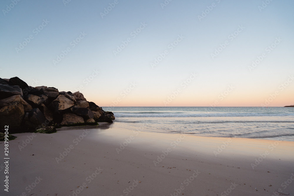 Sunrise over the calm ocean on the beach on a warm summers morning at Trigg beach, Perth, Western Australia.