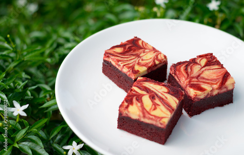 Red velvet cream cheese brownies on white dish
