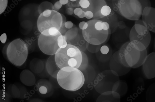The abstract background of white bokeh on a black background.