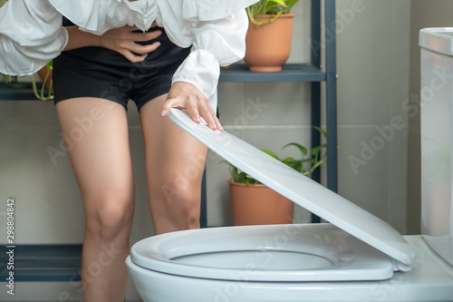woman opening up toilet seat with diarrhea symptom; sick woman suffering from diarrhea, stomachache, menstrual period cramp, abdominal pain, food poisoning, gastritis, constipation; asian woman model
