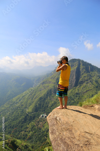 Woman photographer taking photo on the Little Adams peak in Sri Lanka.