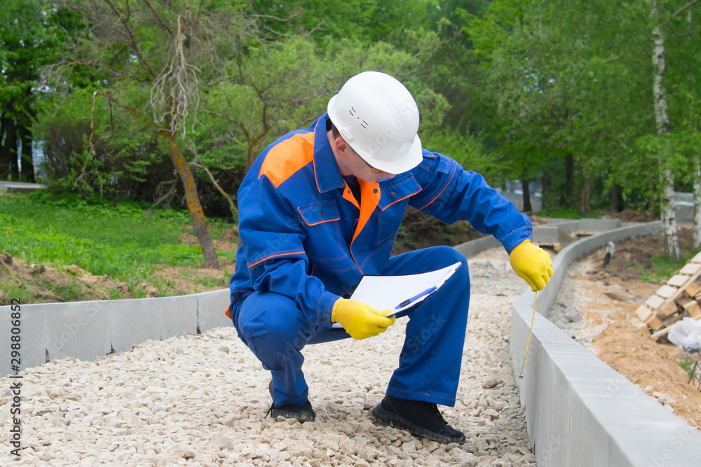 the builder checks the progress of laying curbstones, rubble mounds and keeps records the builder checks the progress of laying curbstones, rubble mounds and keeps records
