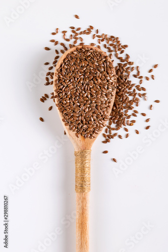 Flax grains, spices in a wooden spoon on a white background. Concept, copy space.