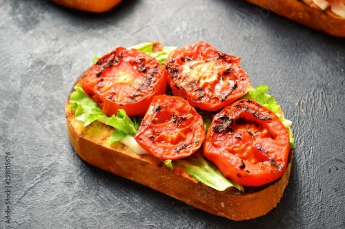 Bruschetta on a dark table background. Bruschetta with grilled  tomatoes, mozzarella and avocado. Delicious vegetarian healthy sandwiches. Tasty snack.