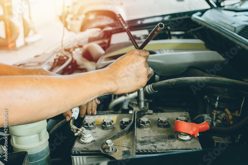 Changing the car battery that does not start. technician man using a wrench, fitting to spinning screws for the auto battery at Service shop