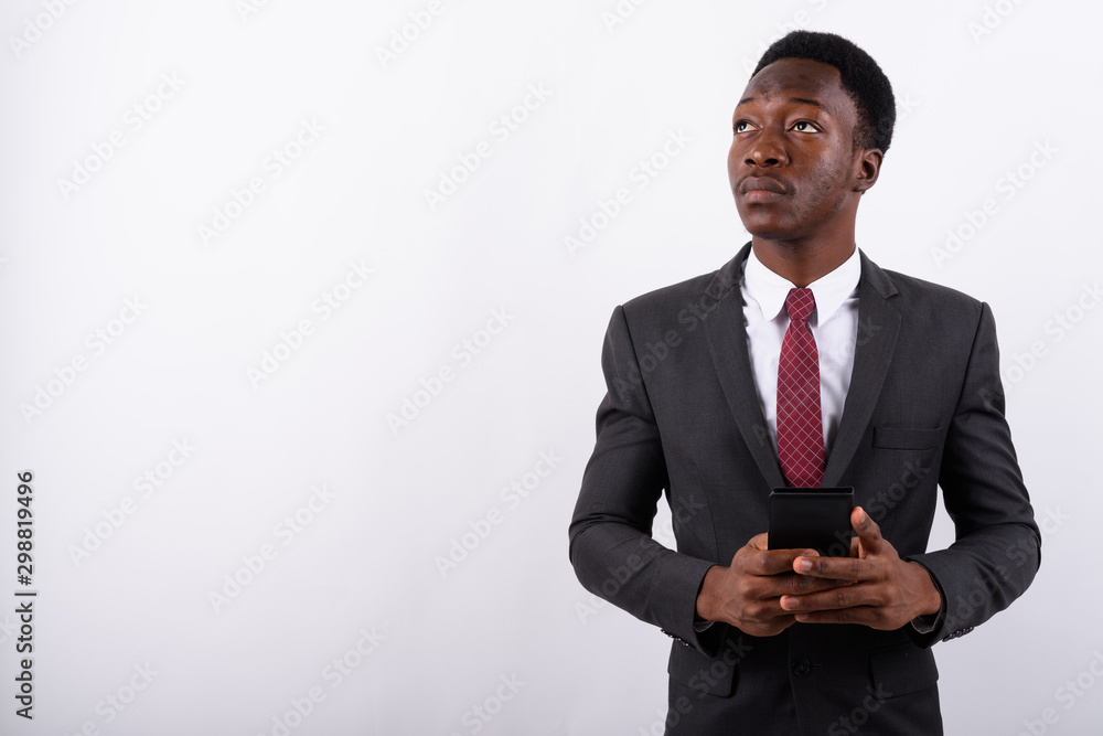 Young handsome African businessman using mobile phone against wh Young handsome African businessman using mobile phone against wh