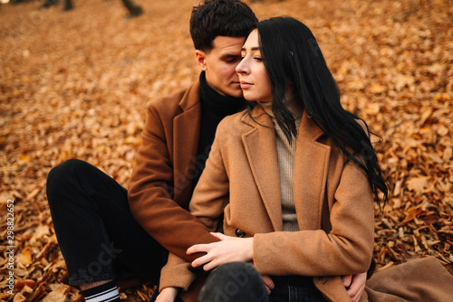 Stylish young couple outdoors on a beautiful autumn day in the forest. Young couple in love holding hands and walking through a park on a autumn day. The concept of youth, love and lifestyle.