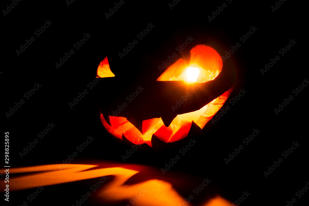 Halloween pumpkin smile and scary eyes for party night. Close up view of scary Halloween pumpkin with eyes glowing inside at black background. Selective focus Halloween pumpkin smile and scary eyes for party night. Close up view of scary Halloween pumpkin with eyes glowing inside at black background. Selective focus